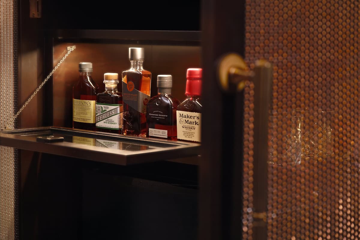 A minibar with various liquor bottles, including brands like Jefferson's and Maker's Mark.