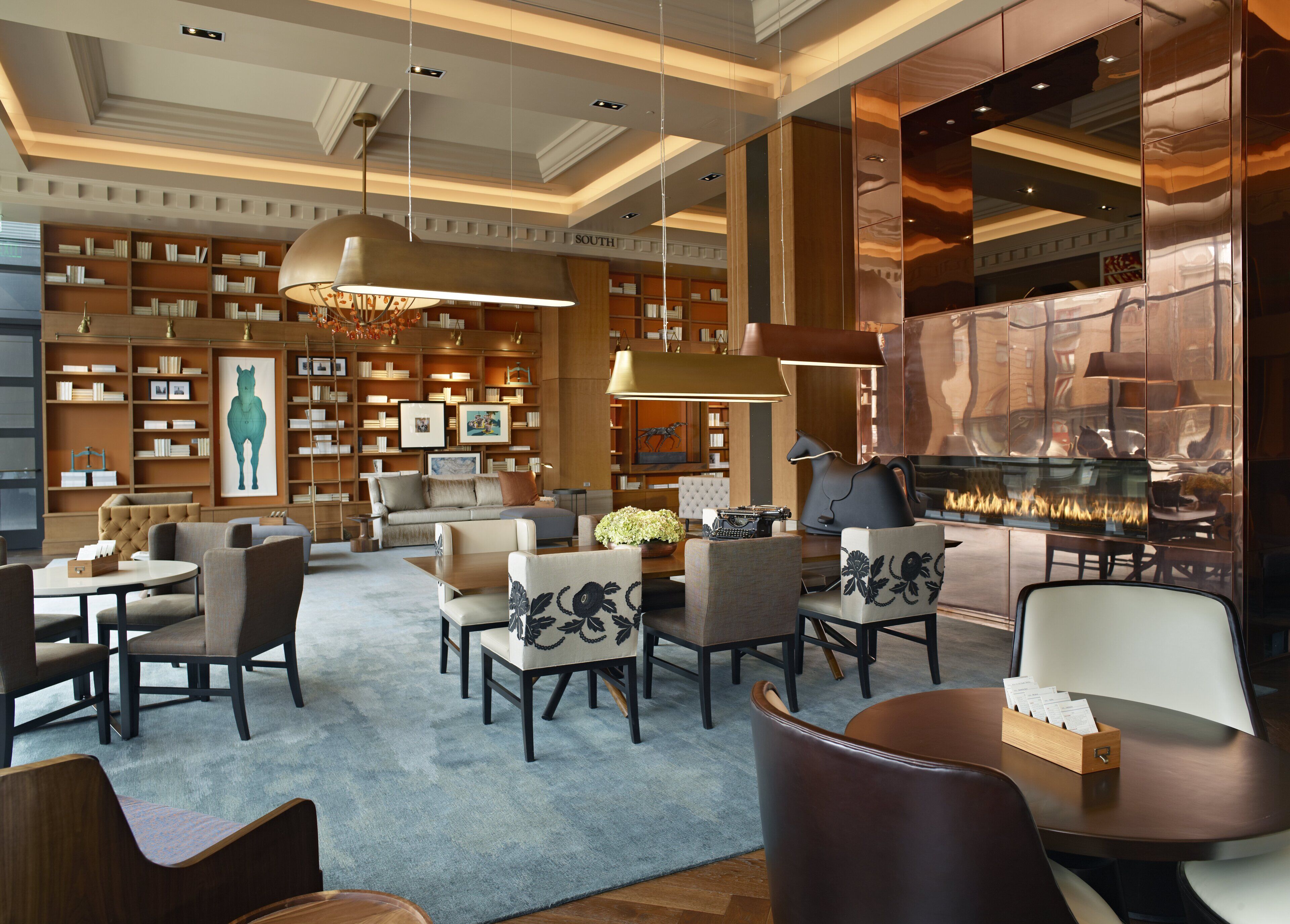 A spacious lobby with a fireplace, comfortable seating, and a large bookshelf.