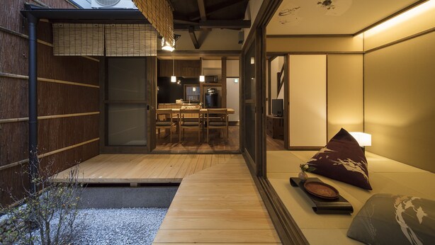 Ett traditionellt japanskt rum med tatamimattor på golvet, ett lågt träbord och en skjutdörr som leder till ett köksområde.