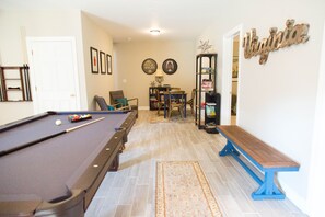 A pool table with a billiard cue and balls, a pool table with a blue bench, a bookshelf, and a door. - In the center of Nelson County's wine and beer region, 19 miles to UVA/Cville (Afton)