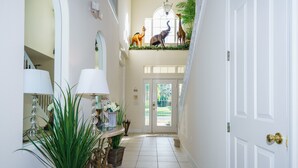 Ein Flur mit einer weißen Tür, einer Treppe und einem Balkon mit Tiermotiven.
