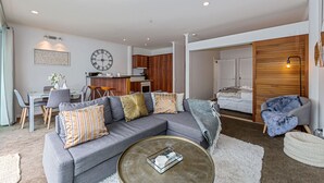 A modern living room with a grey sectional sofa, a coffee table, and a dining area with a white table and chairs. - Premium 1BR Apartment at Princes Wharf (Auckland)