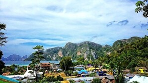 A coastal town with buildings, a beach, and mountains in the background. - View Garden Resort (Ko Phi Phi)