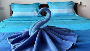 A bed with blue bedding and a towel shaped like a swan. There are three framed botanical prints on the wall behind the bed. - View Garden Resort (Ko Phi Phi)