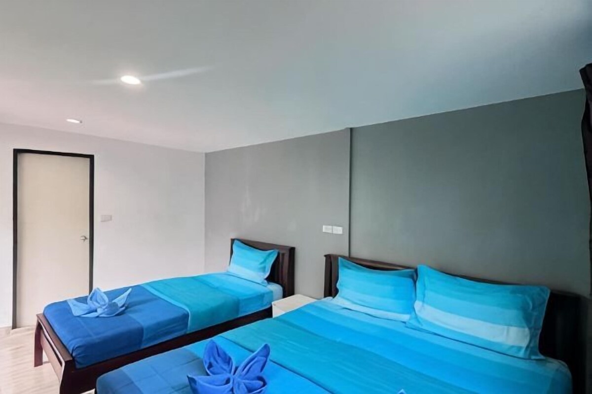 A hotel room with two beds, a door, and a light switch on the wall.