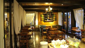 Een restaurant met houten meubels, een kroonluchter en een toonbank met etenswaren.