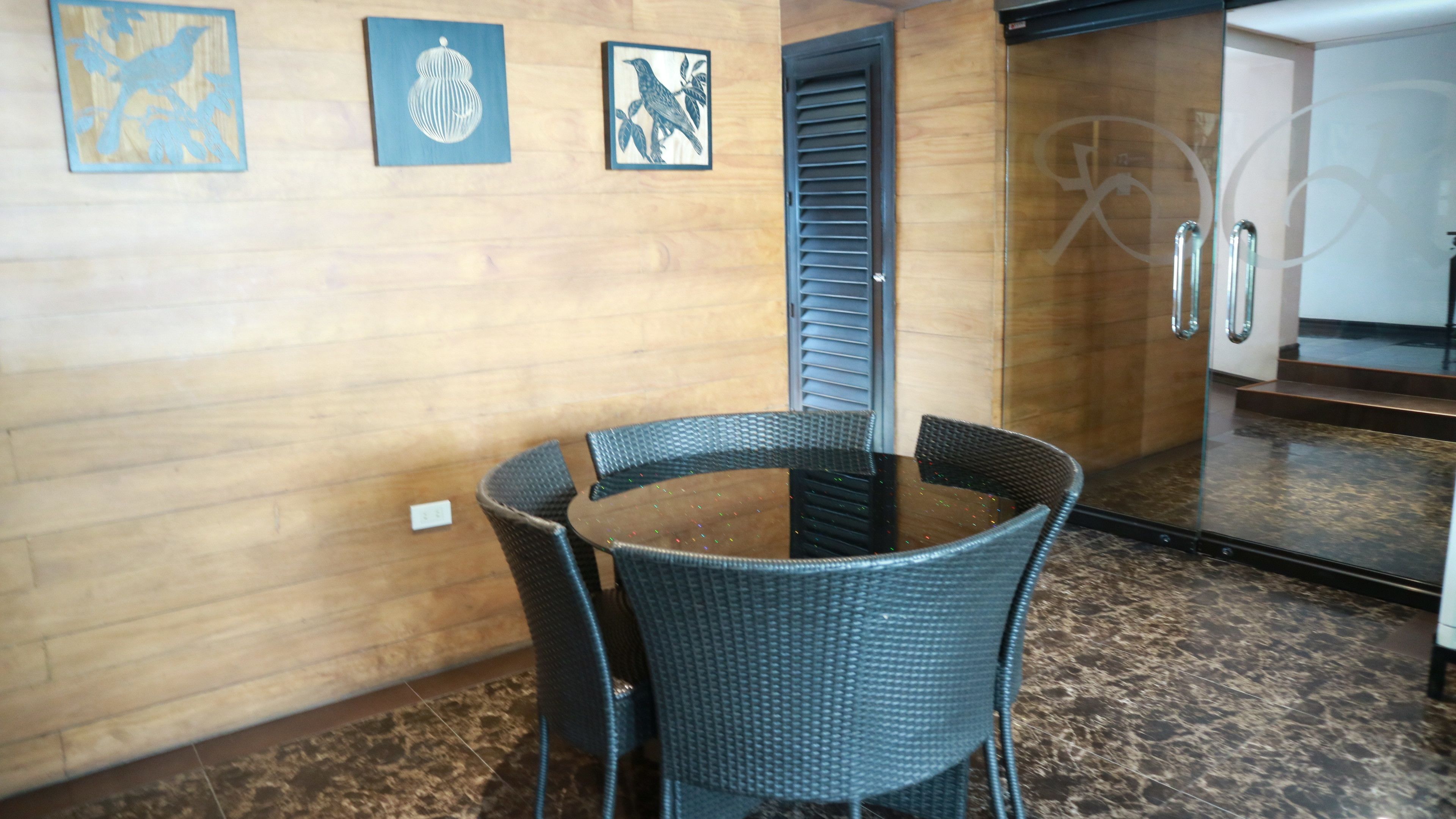 A room with a round table and four chairs, wooden walls, and a mirror with a door.