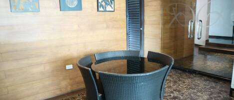 A room with a round table and four chairs, wooden walls, and a mirror with a door.