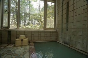 A room with a tiled floor, a window with a view of trees, and a small window seat with two chairs. - Pension Richemond (Kusatsu)