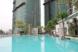 Una piscina rodeada de follaje y edificios modernos al fondo.