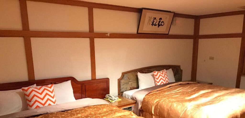 A hotel room with two beds, wooden headboards, and a framed picture on the wall.