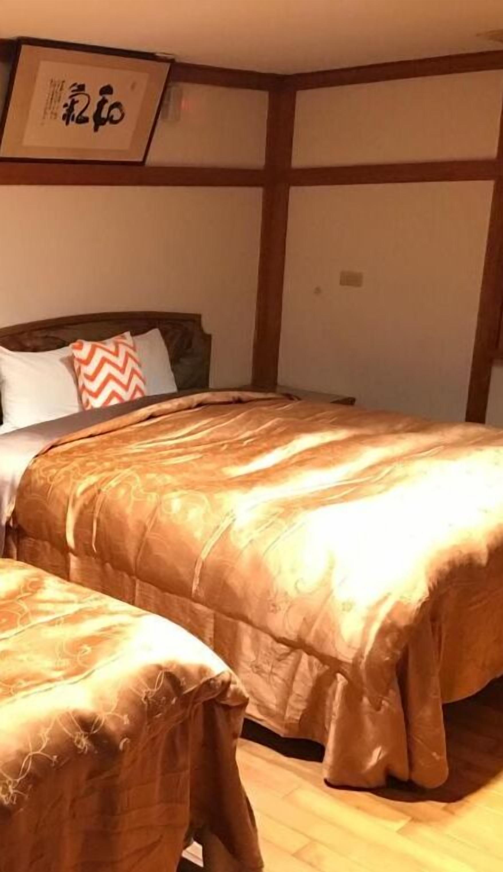 A bedroom with a bed and a nightstand, wooden walls, and a framed picture on the wall.