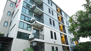 Un immeuble à plusieurs étages doté de balcons, de grandes fenêtres et de climatiseurs.