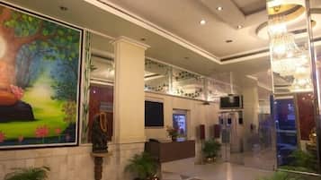 A lobby with a large mural of a meditating figure, a reception desk, and a chandelier.