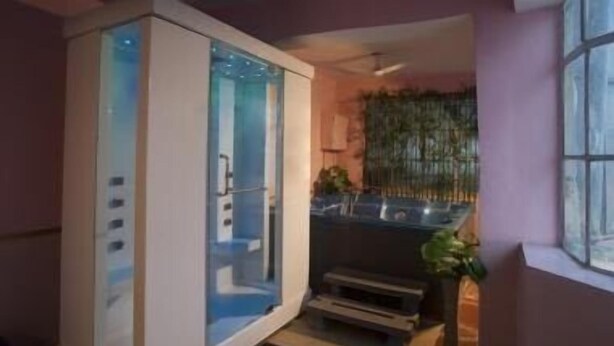 A modern bathroom with a glass enclosure, a sink, and a small step leading to a shower area. - Hotel Samrat International (Patna)