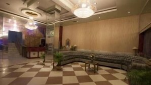 A lobby with a checkered floor, a curved sofa, and a reception desk. - Hotel Samrat International (Patna)