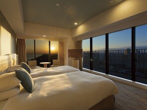 A hotel room with two beds, a view of the cityscape, and a balcony with a railing. - Tokyo Bay Tokyu Hotel (Urayasu)
