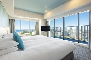 A hotel room with two beds, a TV, and large windows offering a city view.