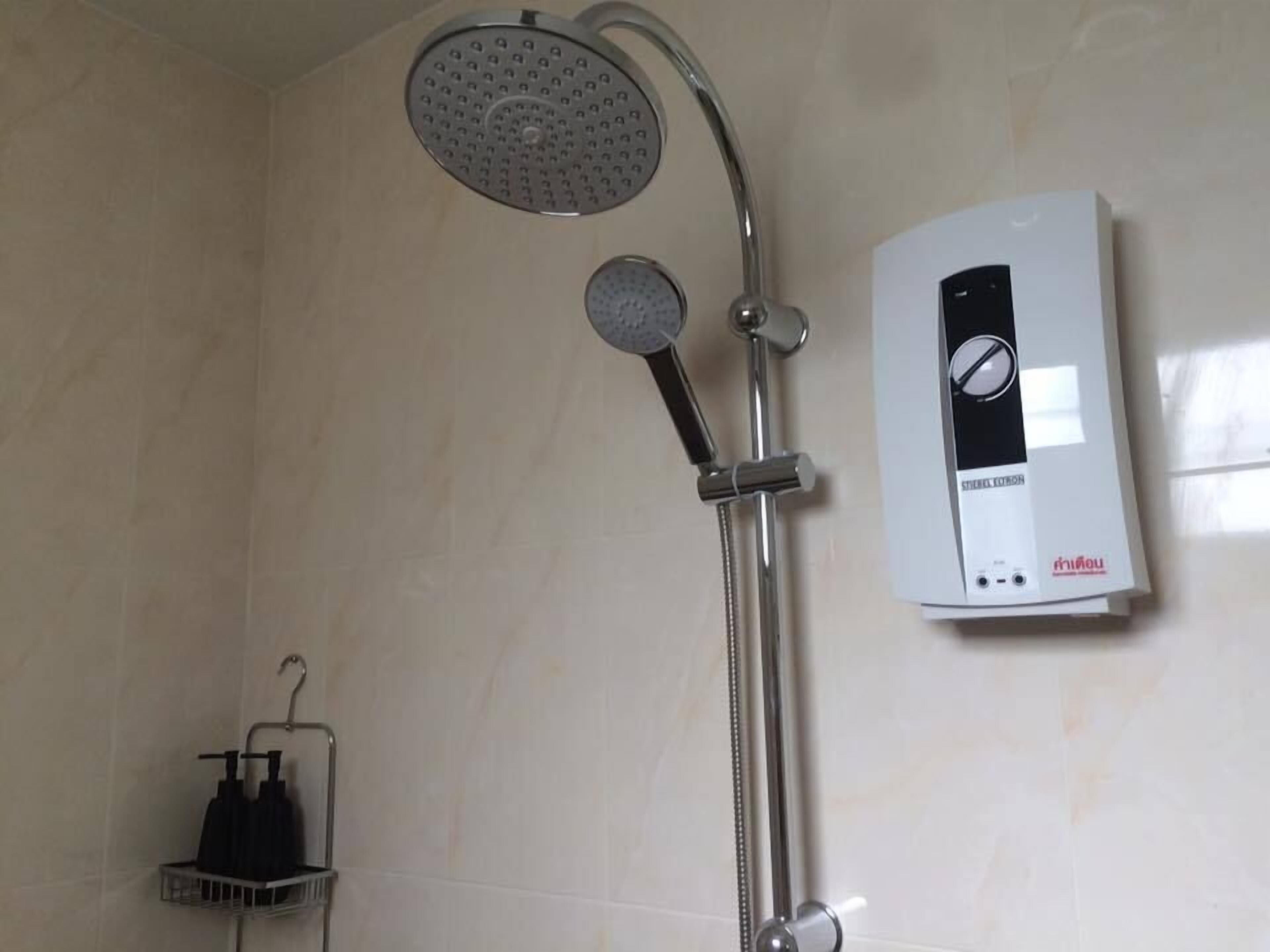 Un baño con ducha, cabezal de ducha de mano y panel de control en la pared.