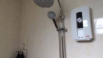 Un baño con ducha, cabezal de ducha de mano y panel de control en la pared.