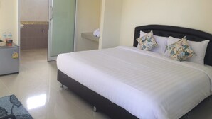 A hotel room with a bed, a desk, a bathroom, and a towel rack. - Baan  Kalaya Garden (Thep Krasattri)