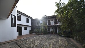 A courtyard with cobblestone flooring, white buildings with balconies, and potted plants. - Hospederia La Fuente (Villa de Leyva)