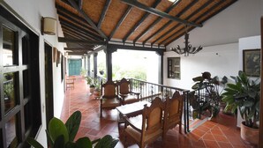 A covered patio area with wooden furniture, potted plants, and a view of the outside. - Hospederia La Fuente (Villa de Leyva)