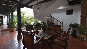 A spacious patio with wooden furniture, a glass-top table, and potted plants. - Hospederia La Fuente (Villa de Leyva)