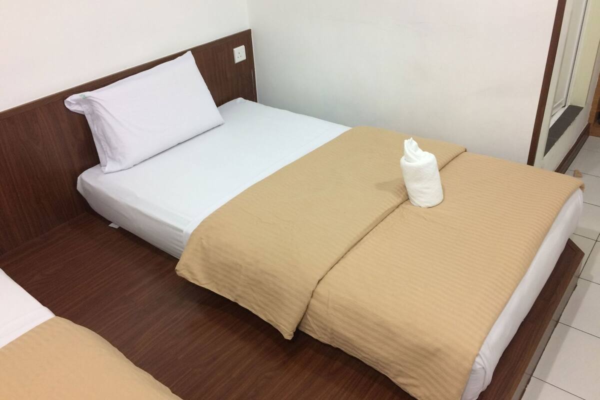 A single bed with a wooden headboard, a beige blanket, and a white pillow.