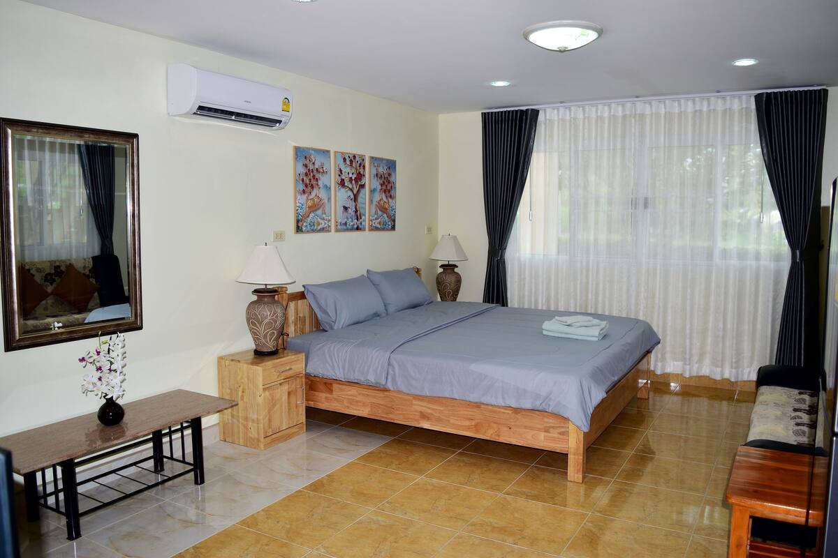 Quarto com cama de madeira, duas mesas de cabeceira, um espelho e obras de arte na parede.