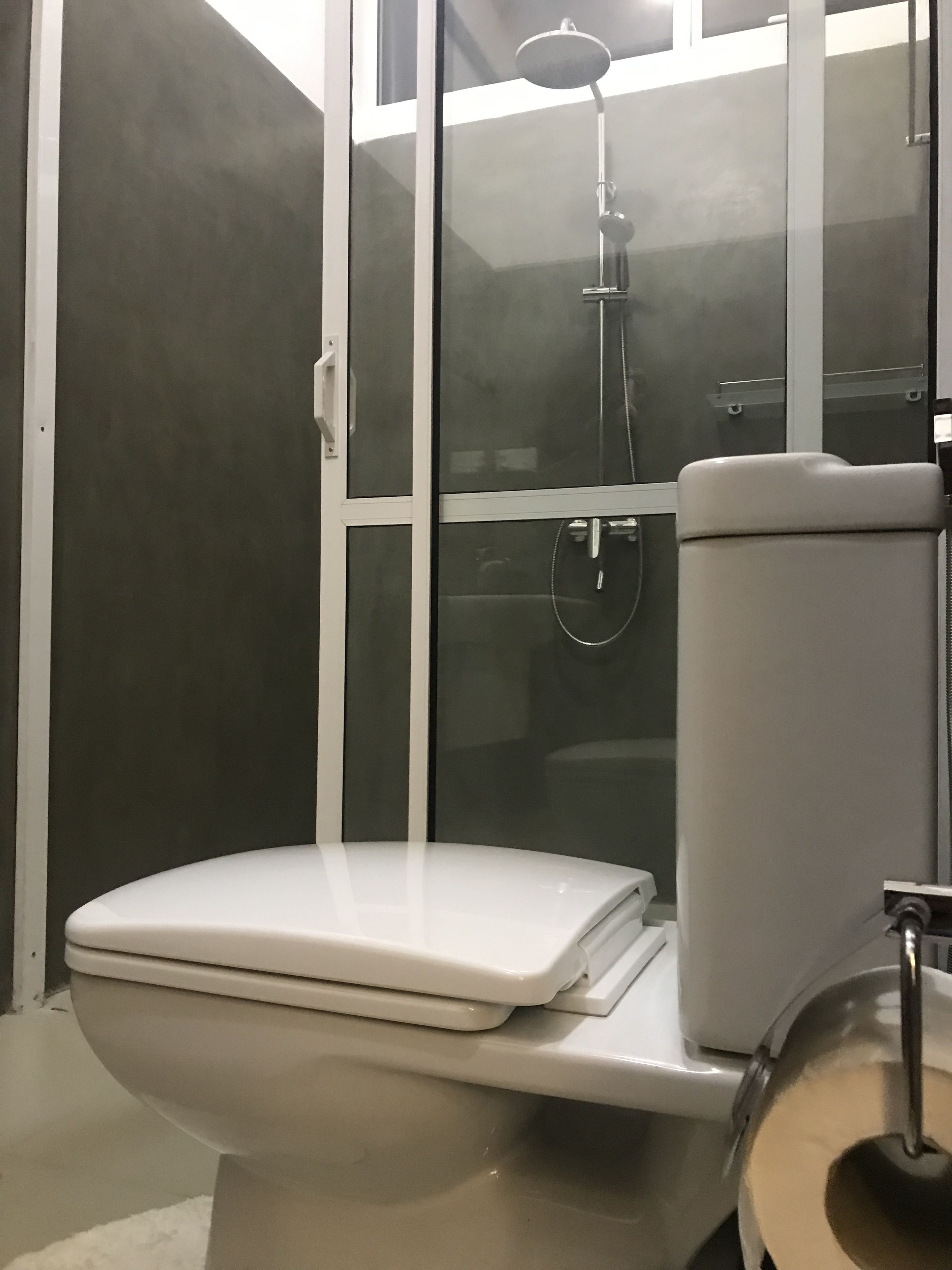 A modern bathroom with a toilet, a glass-enclosed shower, and a toilet paper holder.