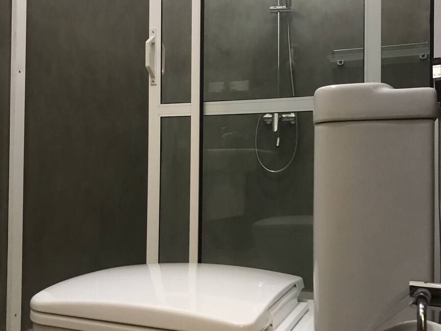 A modern bathroom with a toilet, a glass-enclosed shower, and a toilet paper holder.