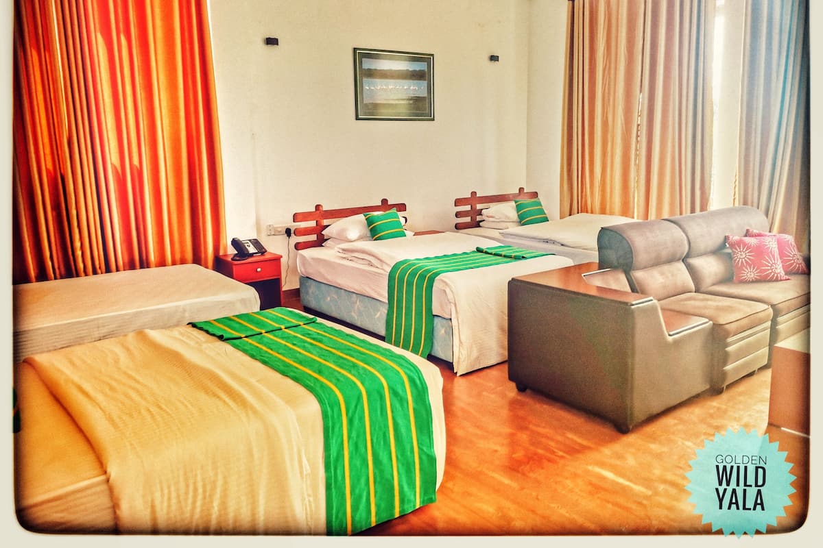 Een hotelkamer met twee bedden, een bank en een nachtkastje.