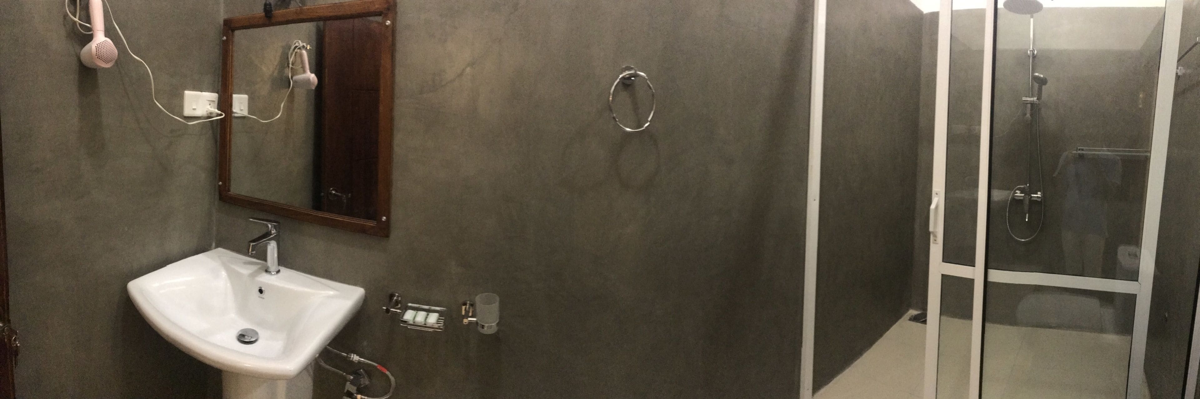 Une salle de bain avec un lavabo blanc, un miroir, un porte-serviettes et une cabine de douche en verre.