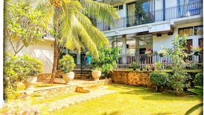 A courtyard with potted plants, a palm tree, and a staircase leading to a balcony.