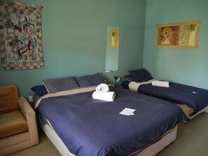 A hotel room with two beds, a sofa, a mirror, and artwork on the walls. - Bon Accord Backpackers (Akaroa)