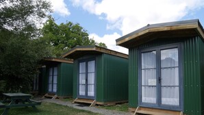 Tres casas móviles verdes con ventanas amplias y una mesa de picnic al frente.