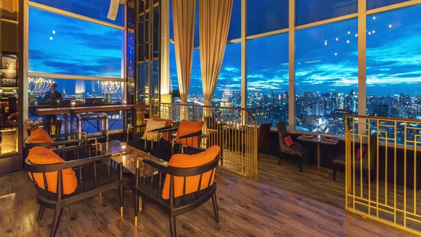 A high-rise hotel room with a city view, large windows, and a bar area. - Bangkok Sky Walk (Bangkok)