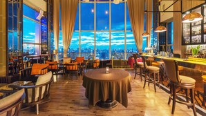 A bar area with a round table, chairs, and a city view through large windows. - Bangkok Sky Walk (Bangkok)