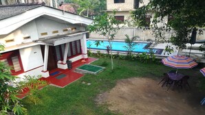 Zona residencial amb una casa, una piscina i un pati amb taula i cadires.