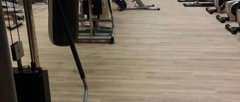 Une salle de sport équipée de divers appareils d’exercice, notamment des tapis de course, des vélos d’appartement et des appareils de musculation.