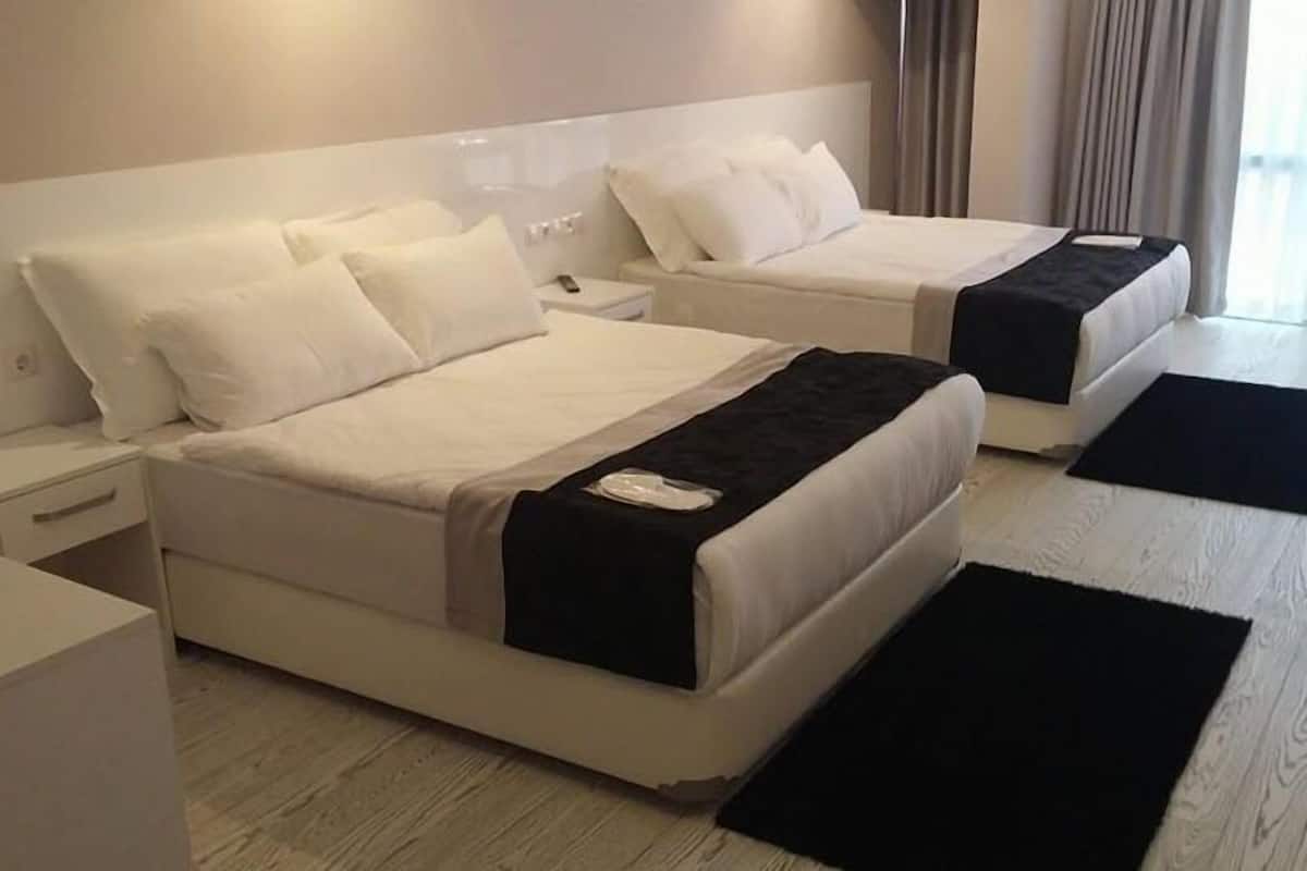 A hotel room with two beds, a desk, and a chair.