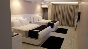 A hotel room with two beds, a flat-screen TV, a bedside table, and a large window with curtains. - Kremon Hotel (Usak)