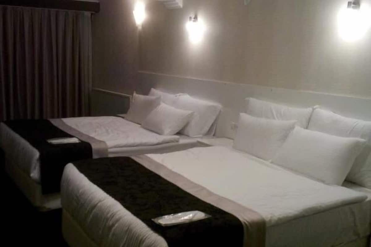 A hotel room with two single beds, a large bed, and a sofa.