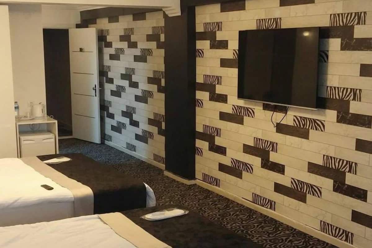 A hotel room with two beds, a flat-screen TV mounted on the wall, and a patterned carpet.