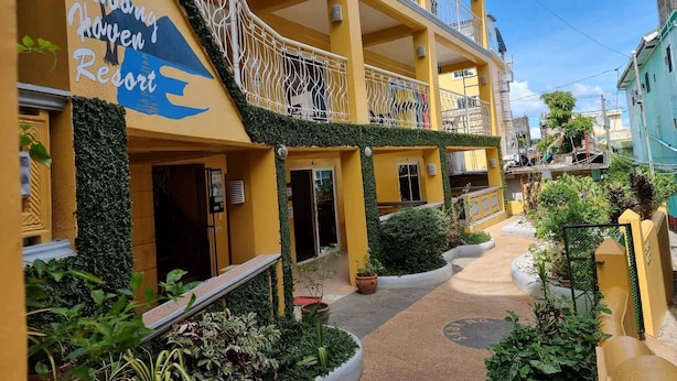 Un immeuble à plusieurs étages doté de balcons, une enseigne indiquant « Salong Haven Resort », et une cour intérieure agrémentée de plantes en pot.