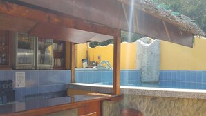 Une cuisine avec un mur en pierre, un coin bar avec des tabourets et une vue sur une piscine.