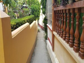 A narrow alleyway with a yellow wall on one side and a wooden balustrade on the other.