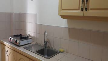 Una cocina con estufa a gas, pileta y muebles color beige.