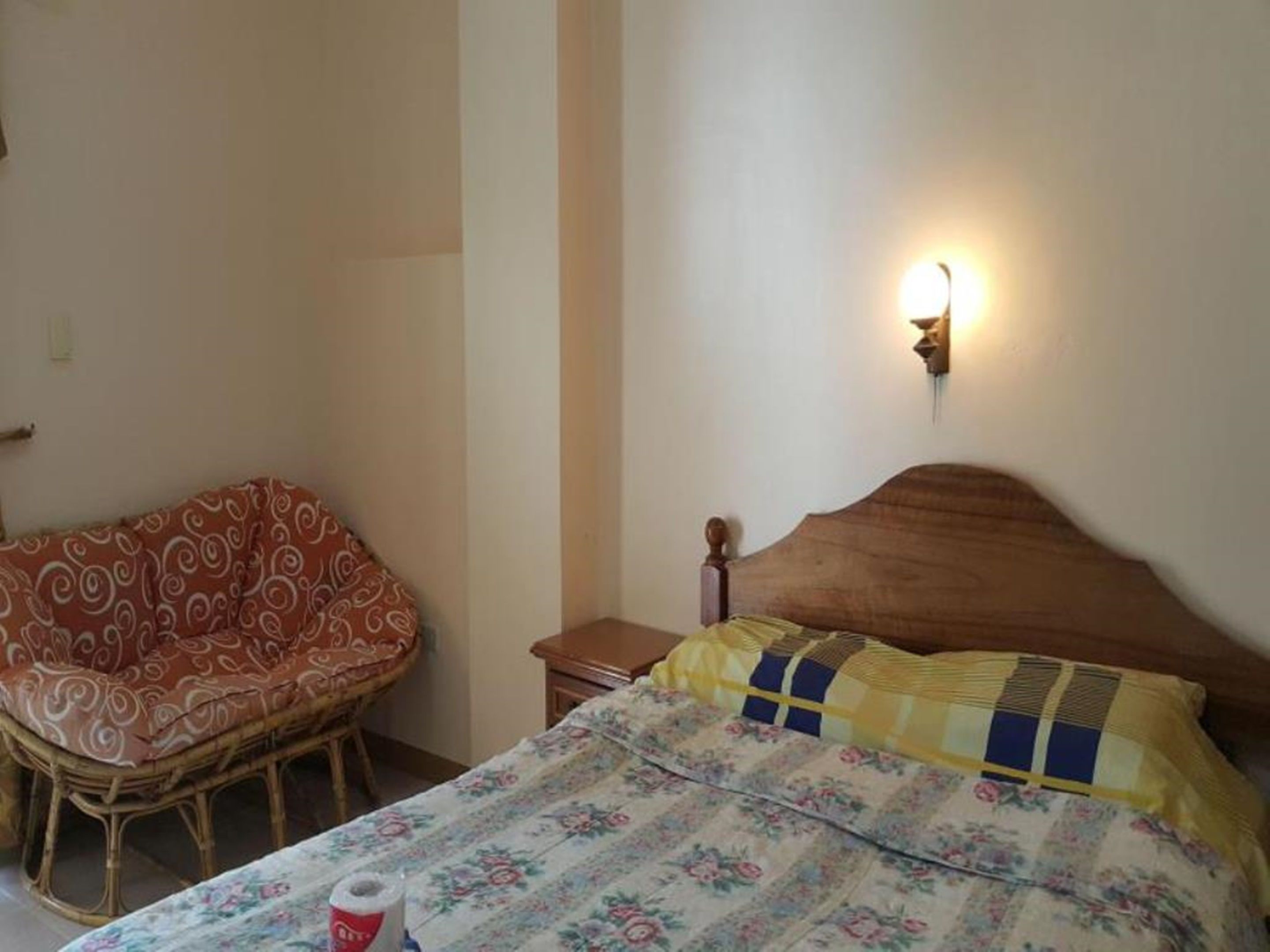A room with a bed, a chair, and a nightstand.